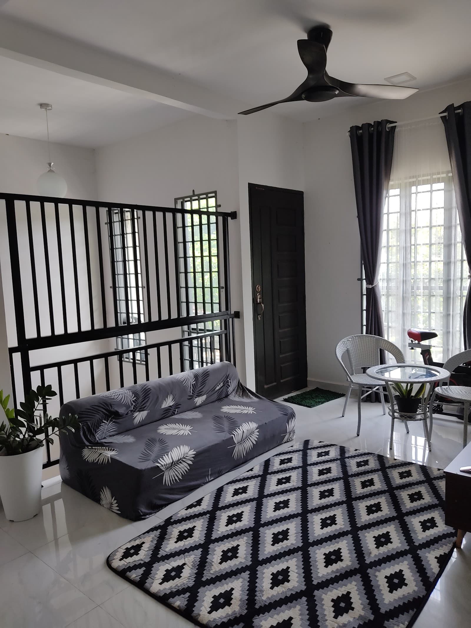 Ruang rehat dengan sofa, meja kecil dan kipas siling